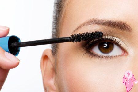 Woman applying mascara on eyelashes